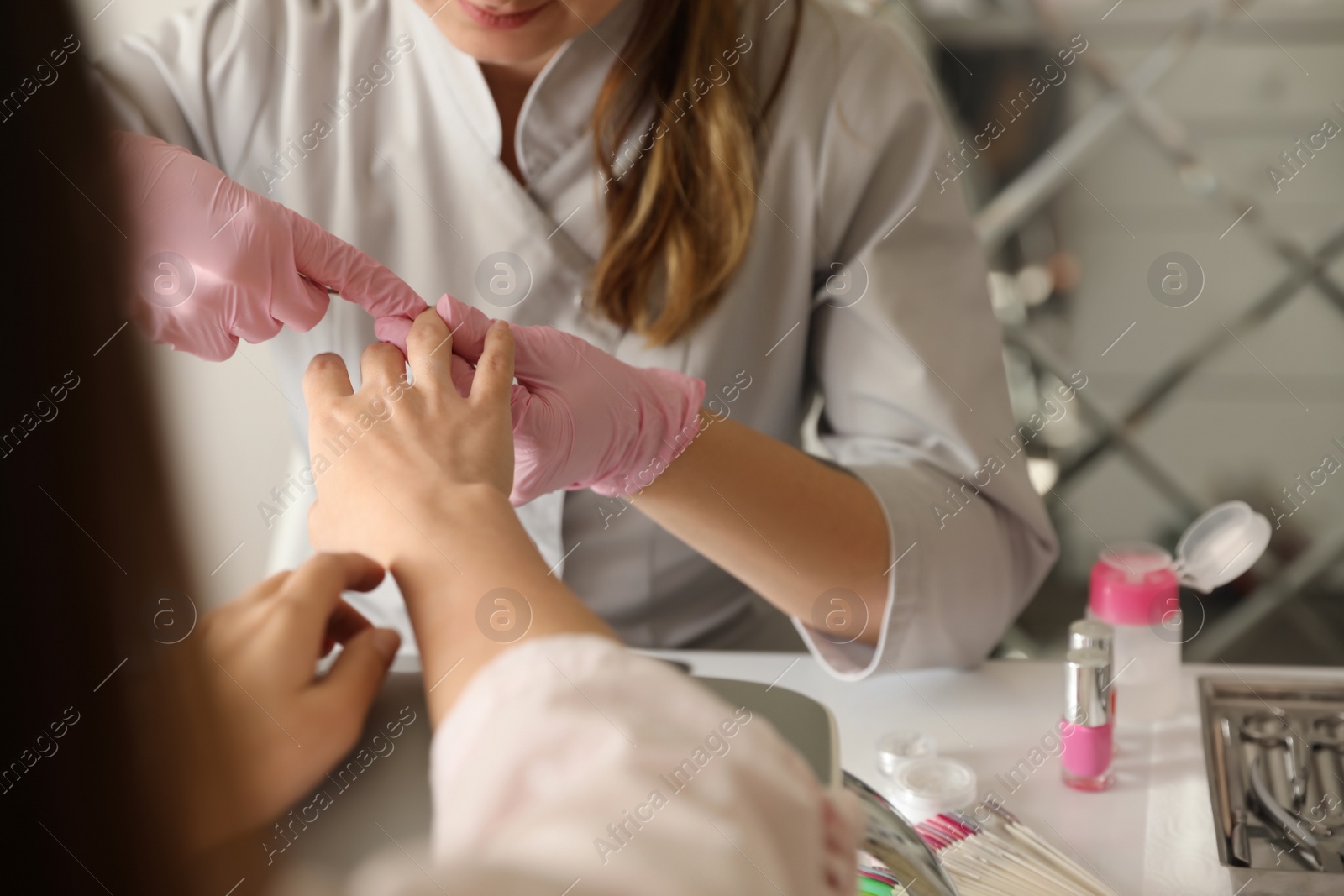 Photo of Professional manicurist working with client in beauty salon, closeup