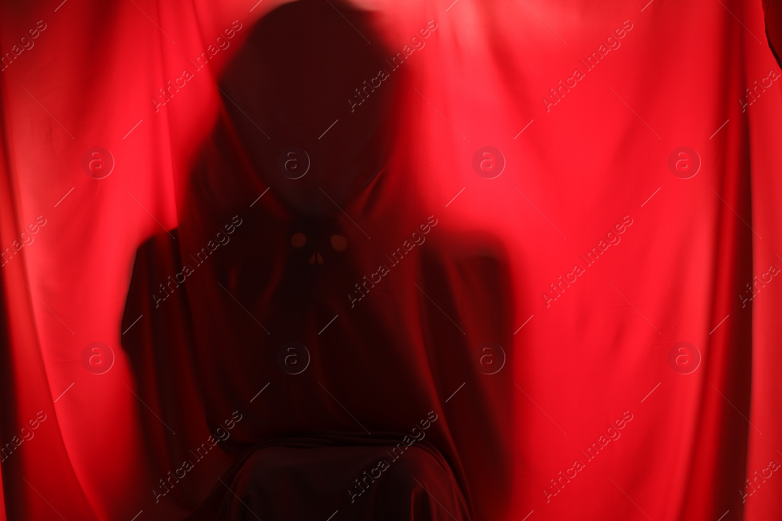 Photo of Silhouette of creepy ghost behind red cloth, space for text