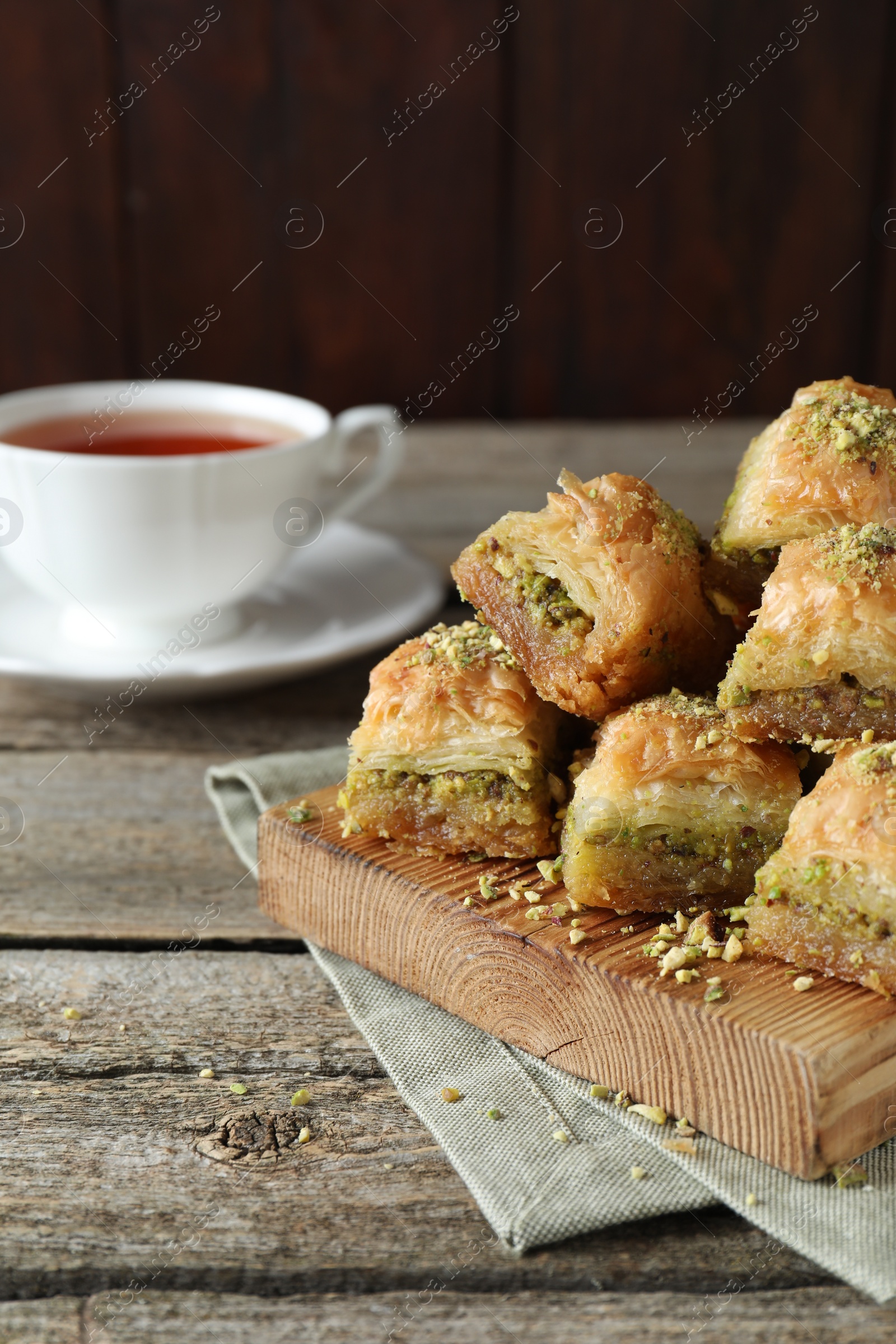Photo of Delicious fresh baklava with chopped nuts on wooden table, space for text Eastern sweets