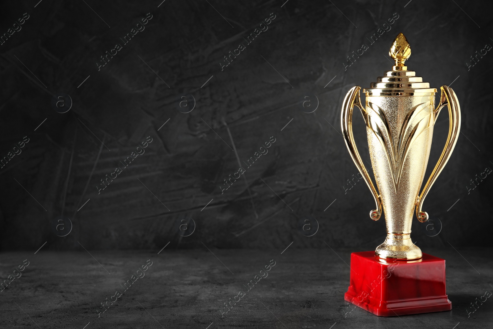 Photo of Golden trophy cup on black background. Space for text