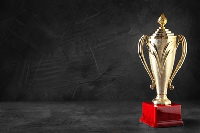 Photo of Golden trophy cup on black background. Space for text