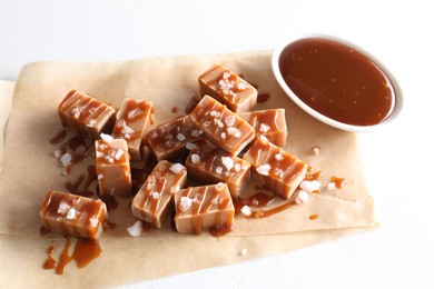 Photo of Tasty candies, caramel sauce and salt on white table, top view