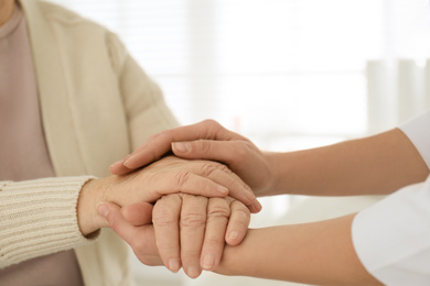 Photo of Doctor holding senior patient's hands in office , closeup