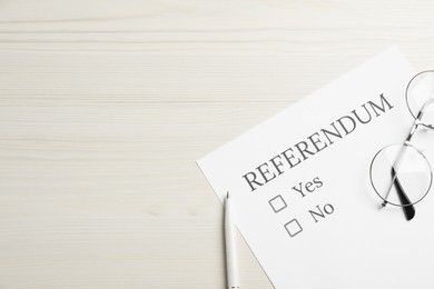 Photo of Referendum ballot with pen and glasses on white wooden table, flat lay. Space for text