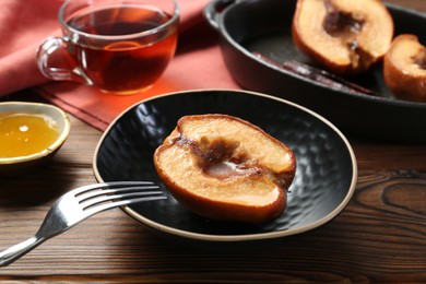 Photo of Tasty baked quince with honey in bowl on wooden table