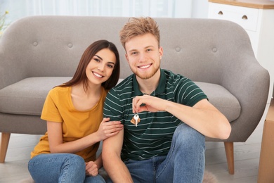 Young couple with key from their new house indoors. Moving day