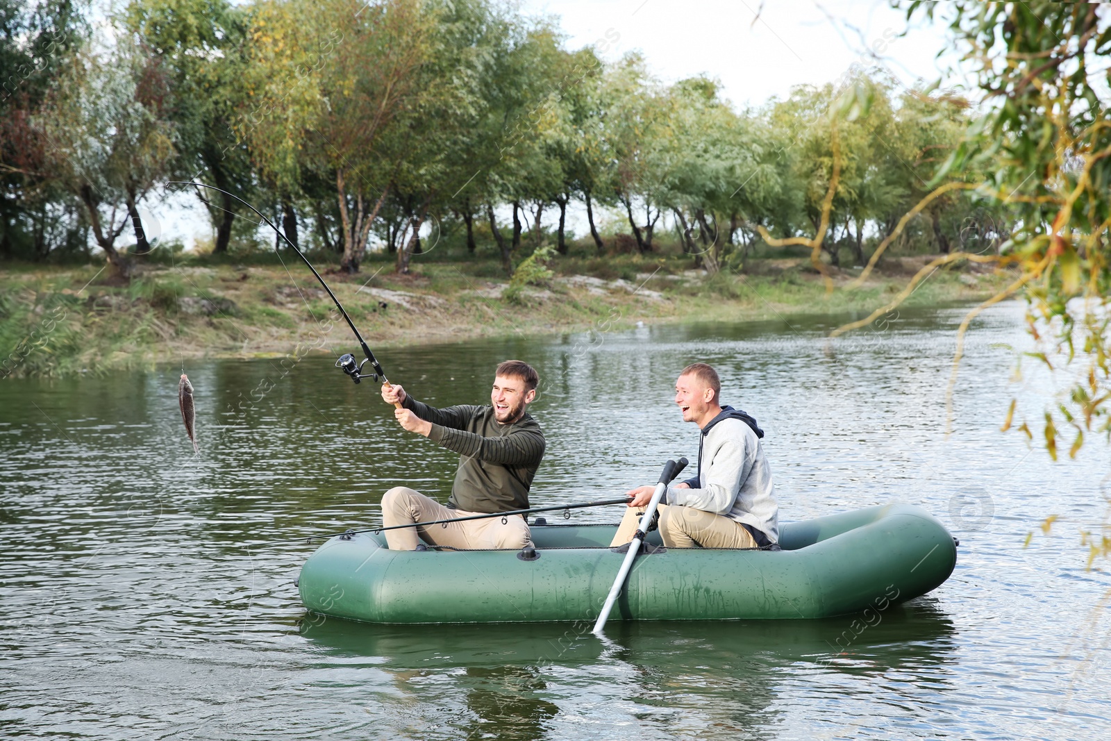 Photo of Friends fishing from boat on river. Recreational activity