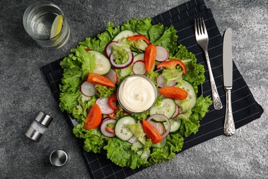 Photo of Plate of delicious vegetable salad with mayonnaise served on grey table, flat lay
