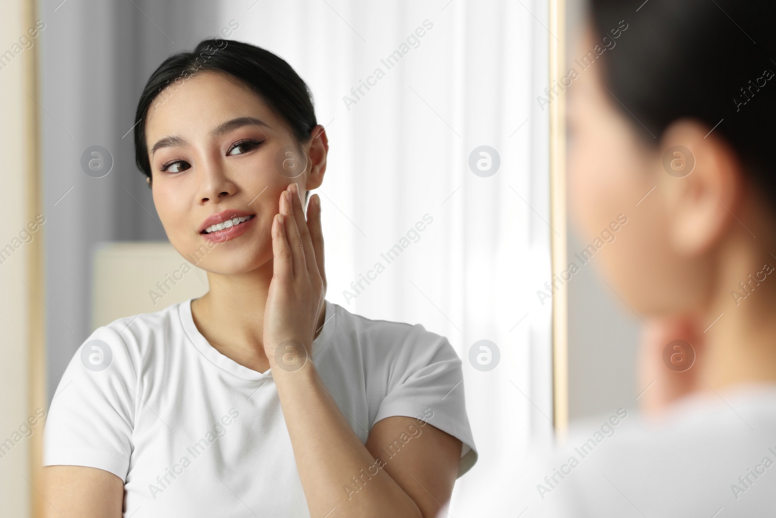 Photo of Portrait of beautiful woman near mirror indoors