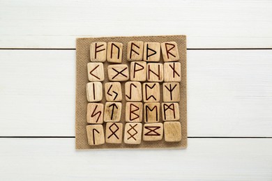 Runes with different symbols on white wooden table, top view