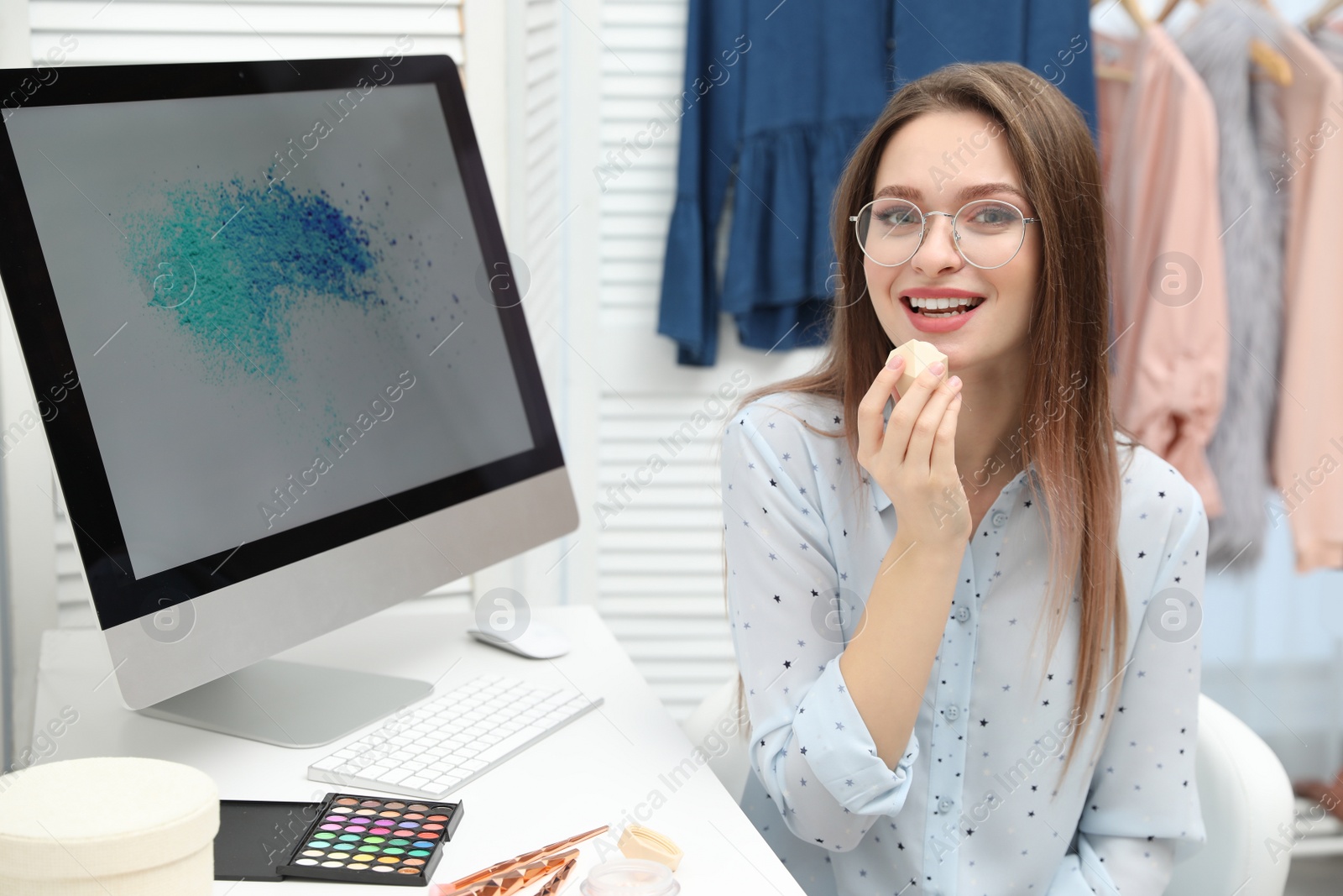 Photo of Beauty blogger applying lip balm at table indoors