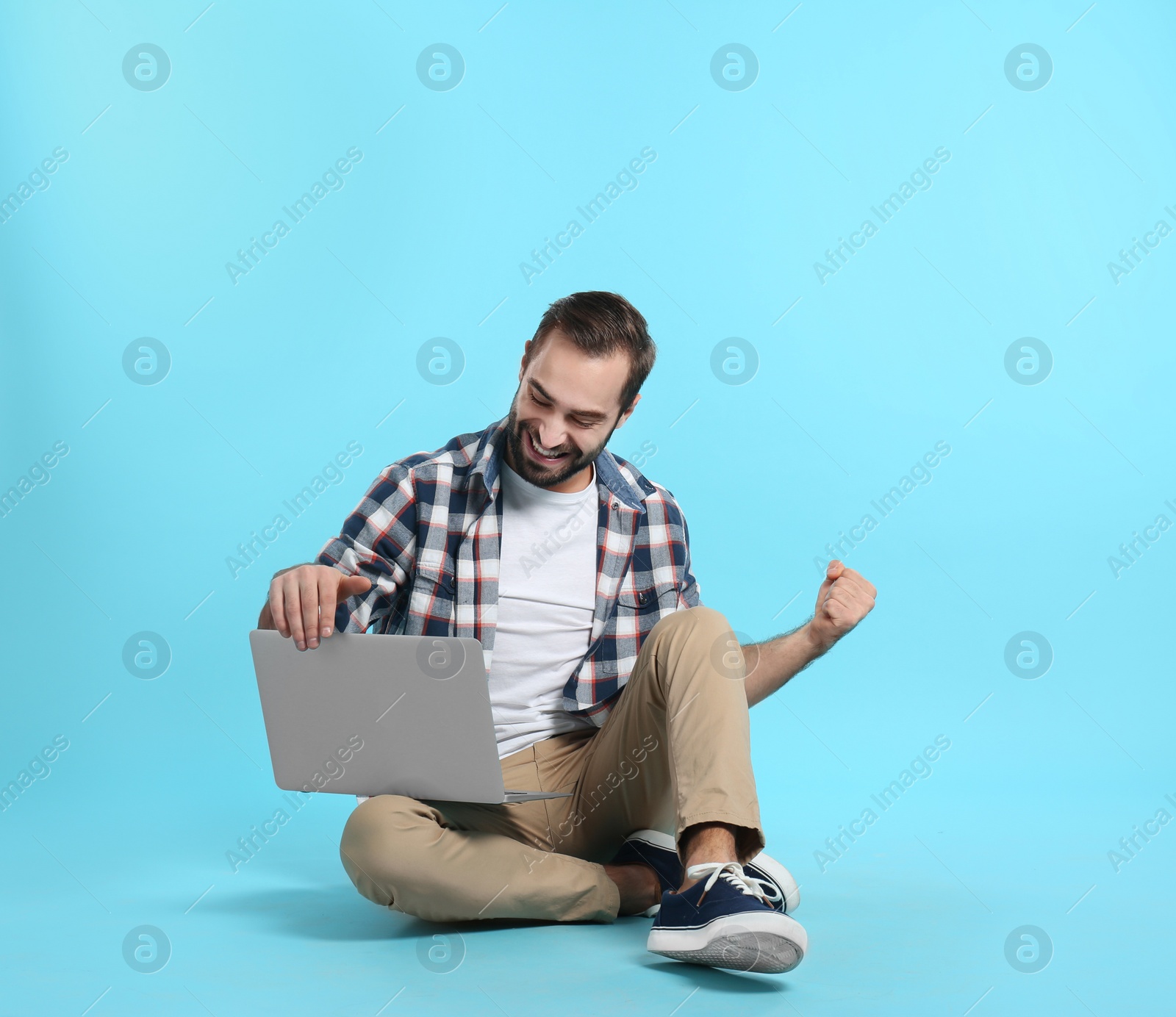 Photo of Emotional young man with laptop celebrating victory on color background