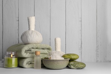 Photo of Composition with different spa products and candle on white table against wooden background. Space for text