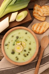 Photo of Delicious leek soup on wooden table, flat lay