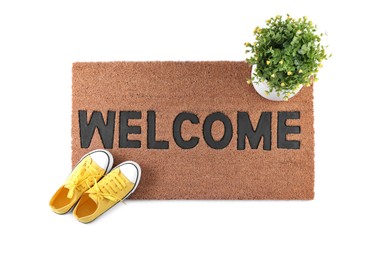 Photo of Stylish door mat with word Welcome, houseplant and shoes on white background, top view