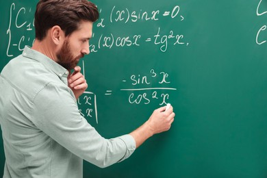 Photo of Mature teacher explaining mathematics at chalkboard in classroom