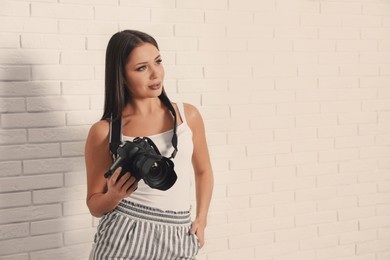 Image of Professional photographer with camera near white brick wall in studio. Space for text