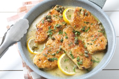 Delicious chicken piccata on white wooden table, closeup