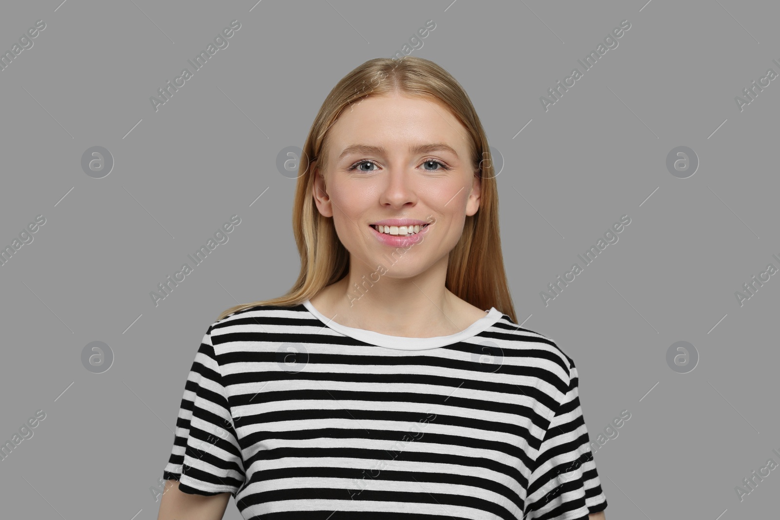 Photo of Portrait of beautiful young woman in striped t-shirt on grey background