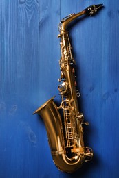 Photo of Beautiful saxophone on blue wooden background, top view