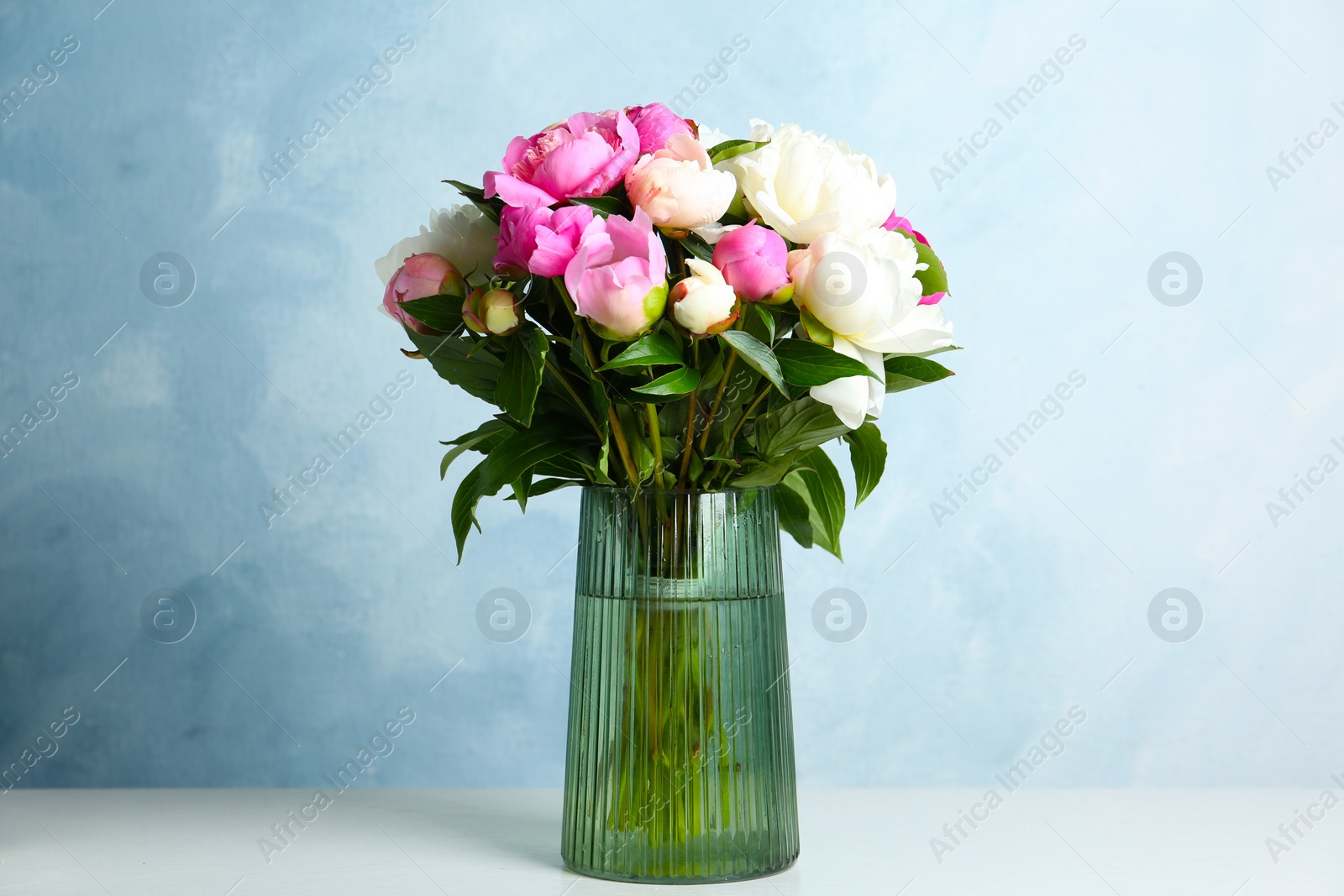 Photo of Bouquet of beautiful peonies in vase on white table