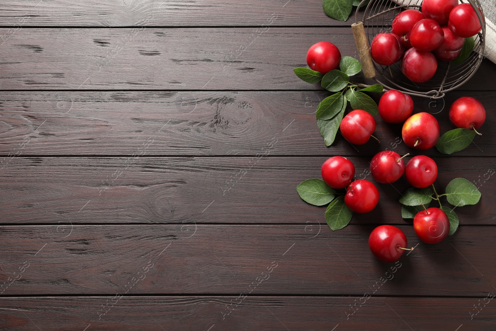 Photo of Delicious ripe cherry plums with leaves on wooden table, flat lay. Space for text