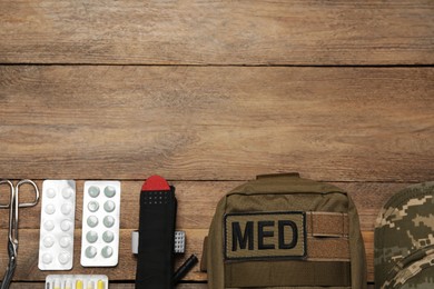 Photo of Flat lay composition with military first aid kit on wooden table. Space for text