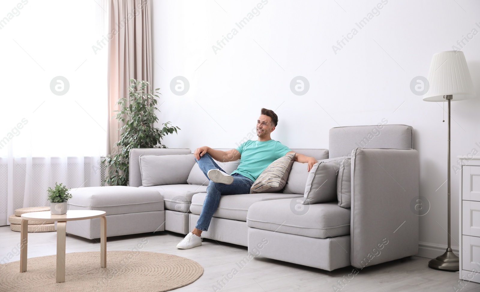 Photo of Young man relaxing on sofa under air conditioner at home