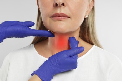 Image of Endocrinologist examining thyroid gland of patient on light grey background, closeup