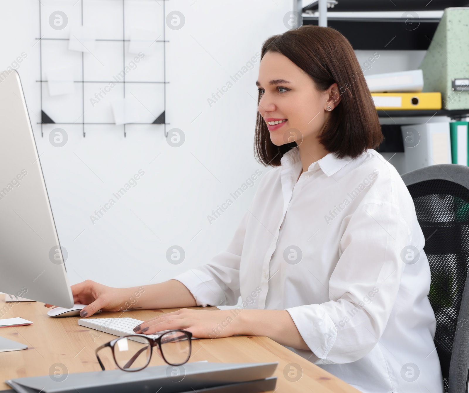 Photo of Happy young intern working with computer at table in modern office