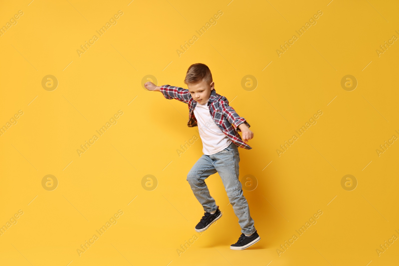 Photo of Happy little boy dancing on yellow background