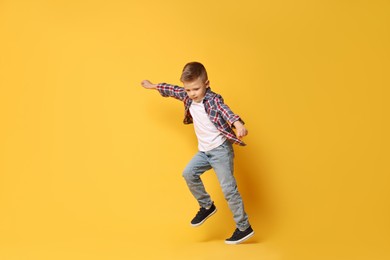 Happy little boy dancing on yellow background