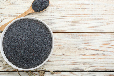 Photo of Poppy seeds in bowl and spoon on white wooden table, flat lay. Space for text