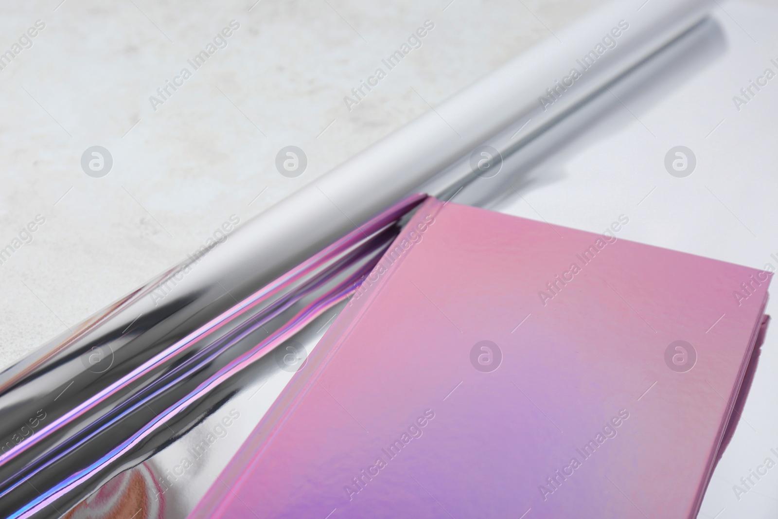 Photo of Beautiful notebook and rolled glossy wrapping paper on table