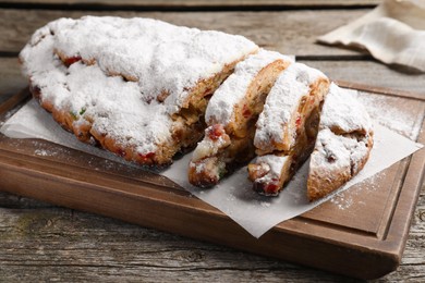 Photo of Traditional Christmas Stollen with icing sugar on wooden table