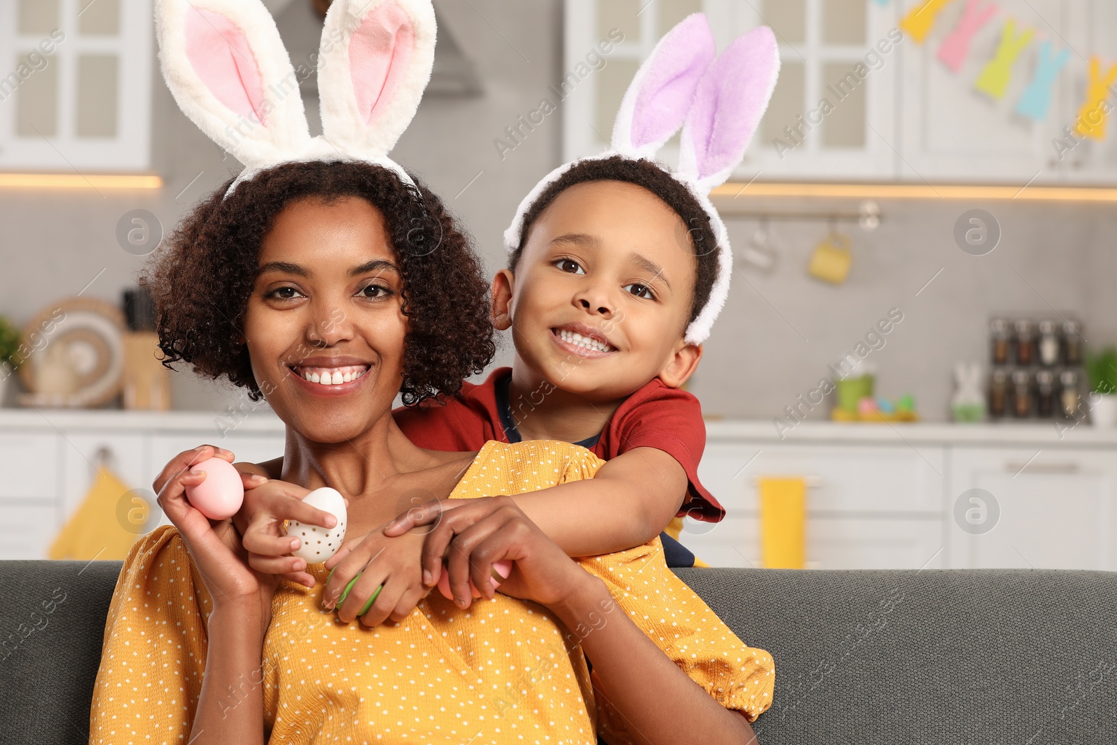 Photo of Happy African American mother and her cute son with Easter eggs in kitchen