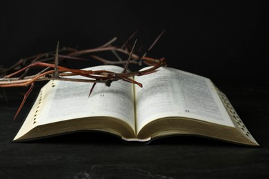 Photo of Bible and crown of thorns on black table