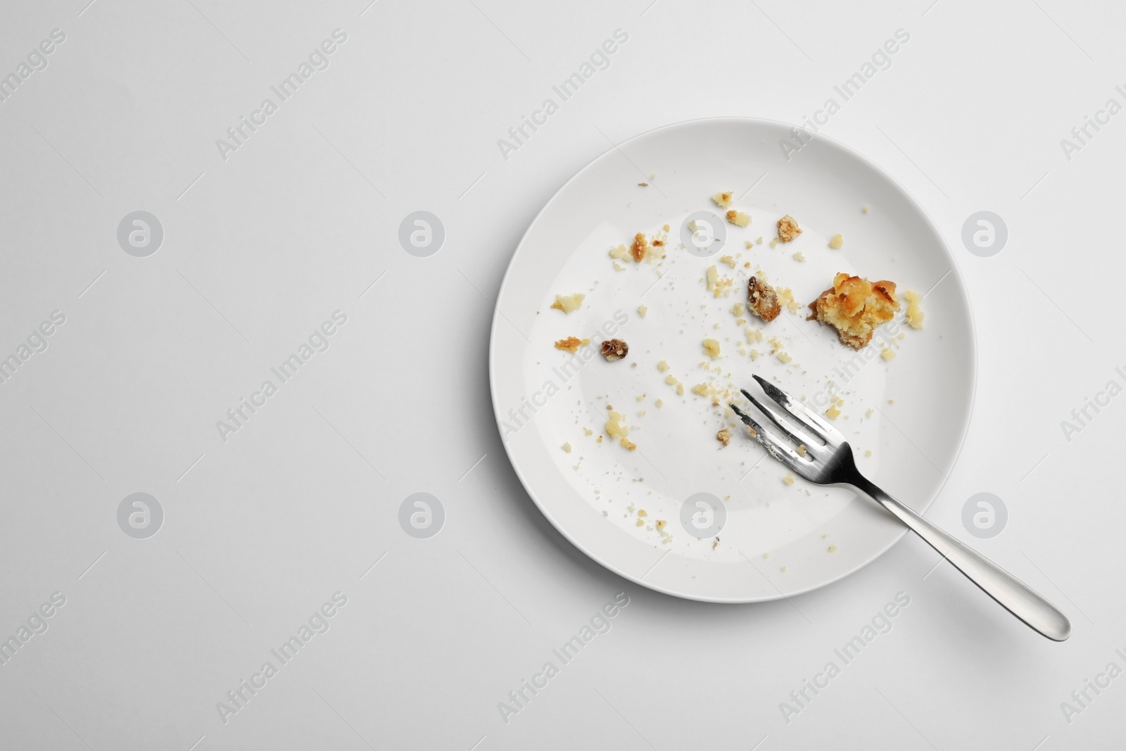 Photo of Dirty plate with food leftovers and fork on white background, top view