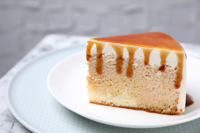 Photo of Slice of delicious cake with caramel sauce on table