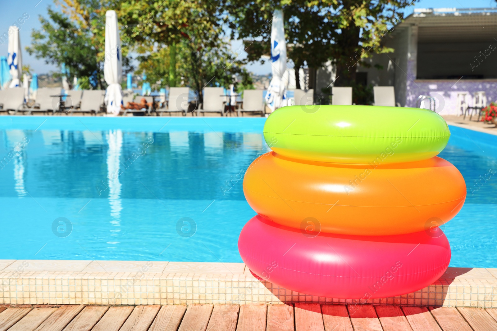 Photo of Modern swimming pool with inflatable rings outdoors. Space for text