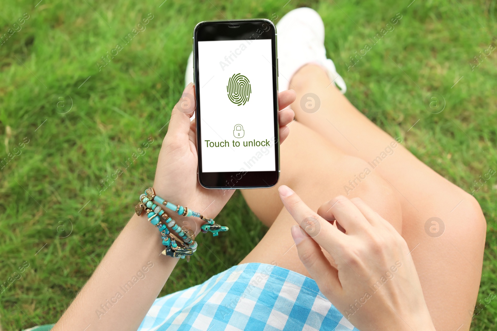 Image of Woman holding smartphone with fingerprint sensor outdoors, closeup. Digital identity