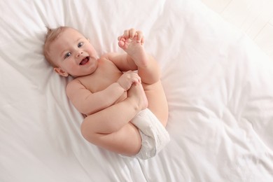 Photo of Cute little baby lying on bed, top view. Space for text