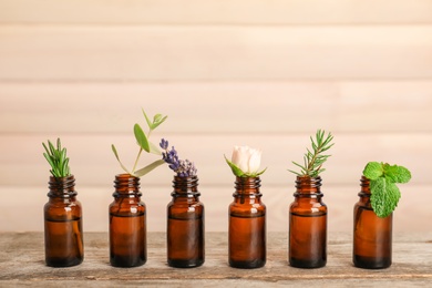 Photo of Glass bottles with different essential oils and herbs on wooden background