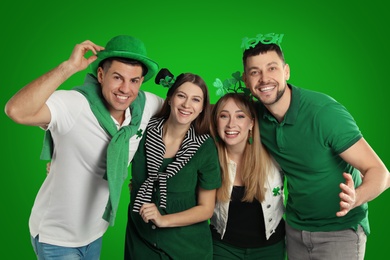 Happy people in St. Patrick's Day outfits on green background