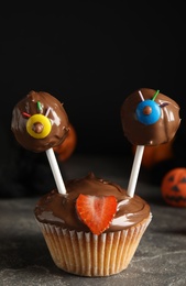 Photo of Delicious desserts decorated as monsters on grey table. Halloween treat