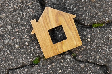 Photo of Wooden house model on cracked asphalt, top view. Earthquake disaster