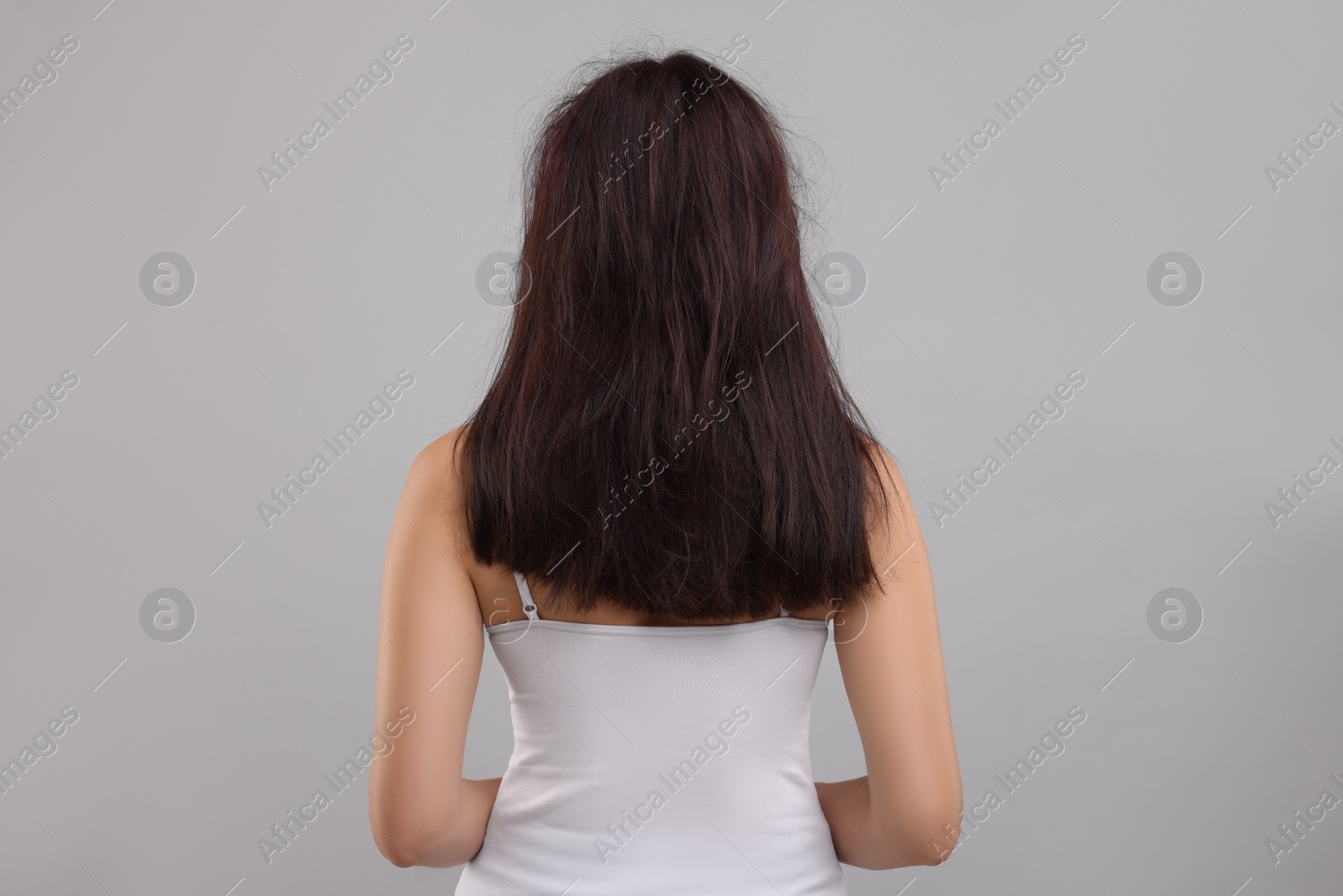 Photo of Woman with damaged hair on light grey background, back view