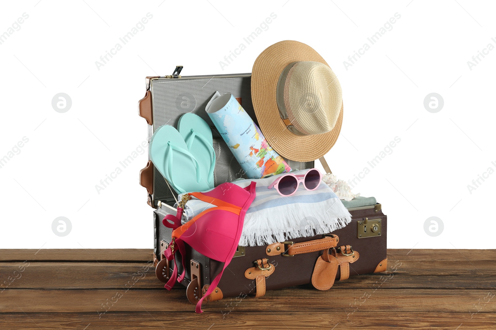 Photo of Open vintage suitcase with different beach objects packed for summer vacation on wooden table against white background