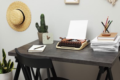 Photo of Typewriter and stack of papers on dark table in room. Writer's workplace