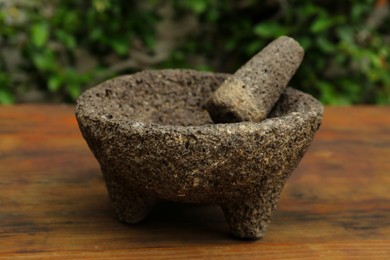 Empty stone mortar with pestle on wooden table outdoors, closeup